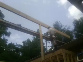 Carpenter setting a ridge beam over a new addition frame — Ice Dam Removal by Roofing Brothers in Riegelwood