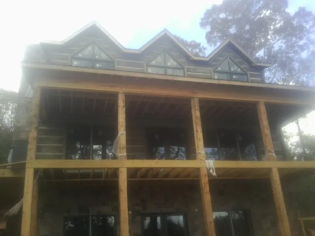 Dormers and porch framing on a large log home under construction — Roof Coating work by our crew in Riegelwood
