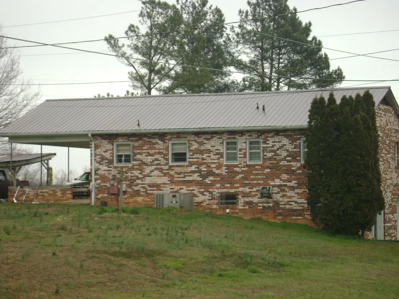 Gray metal roof on a brick split level home with a carport in Riegelwood
