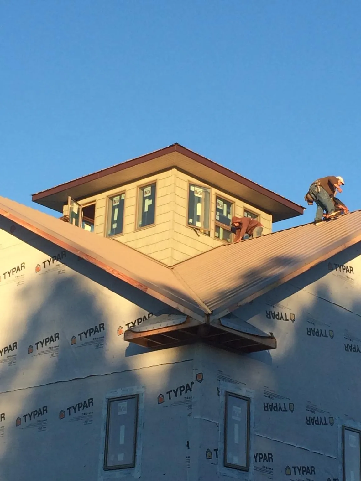 Roofers working around a rooftop cupola on a new metal roof at sunset — Roof Waterproofing in Riegelwood by Roofing Brothers